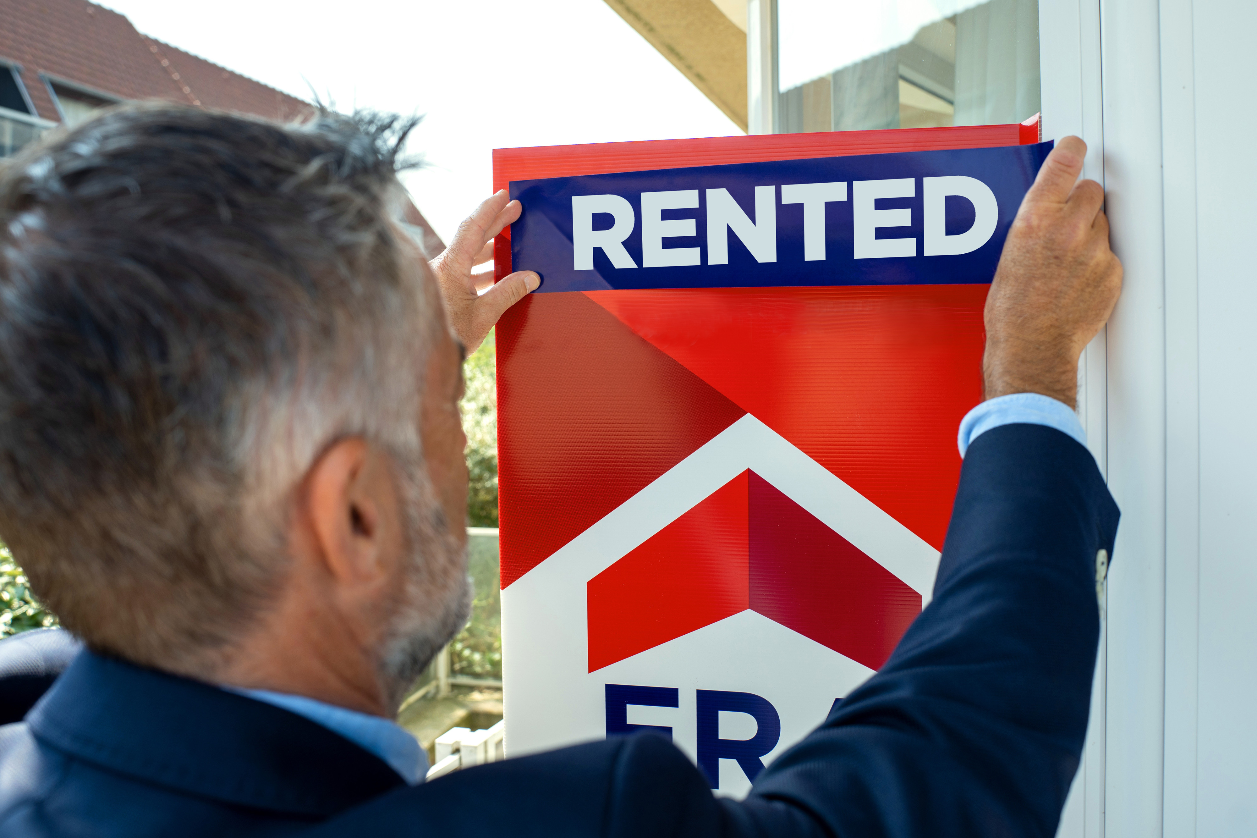 The real estate agent puts rented on the sign