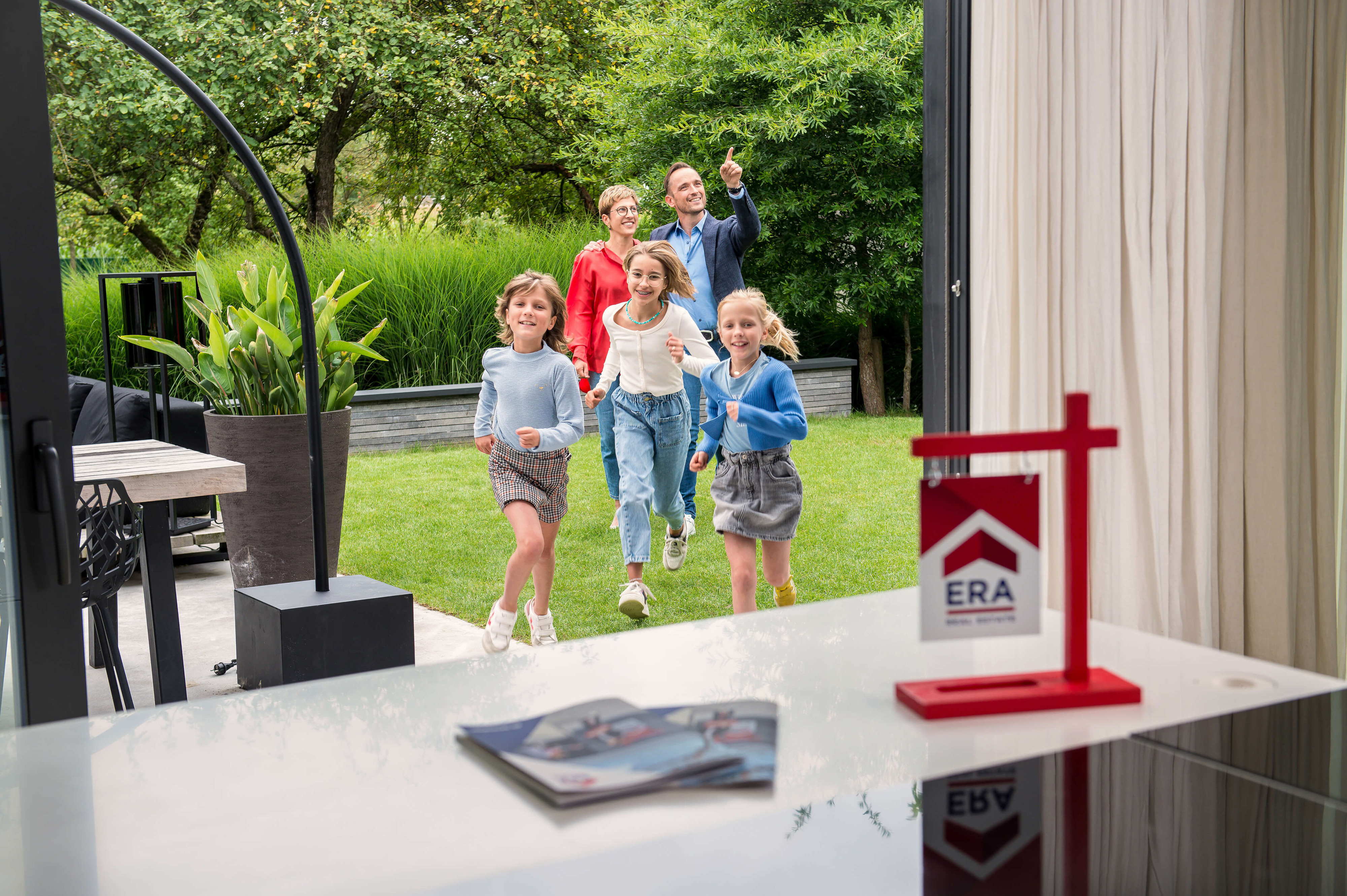 Een gezin komt een woning bezoeken, de kinderen lopen met drie heel enthousiast naar binnen.