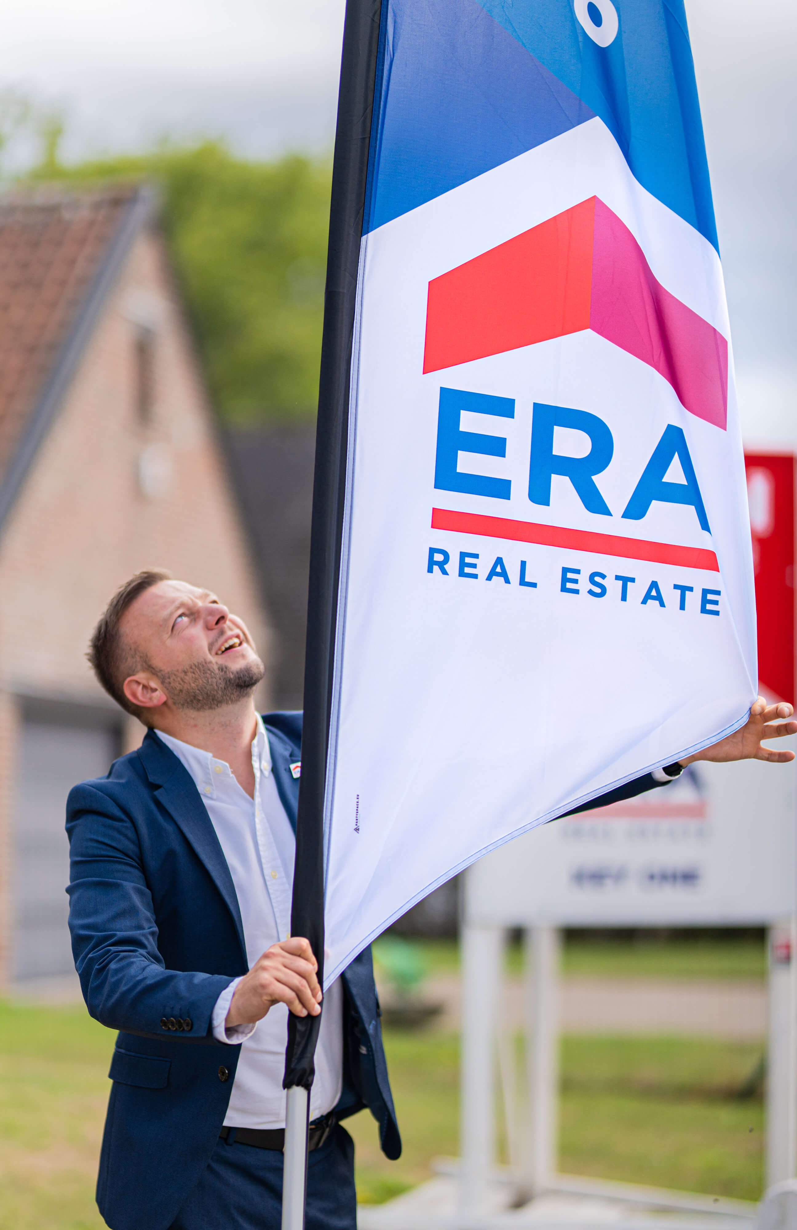 Een ERA makelaar zet een ERA Open Huizen Dag beachvlag op zijn plaats.