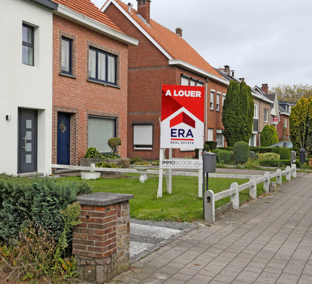 Il y a un grand panneau en V rouge dans le jardin avant d'une maison qui est mise en vente par ERA.