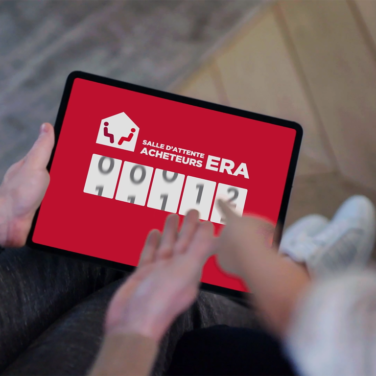 Deux personnes regardent la Salle d'Attente Acheteurs ERA sur une tablette.