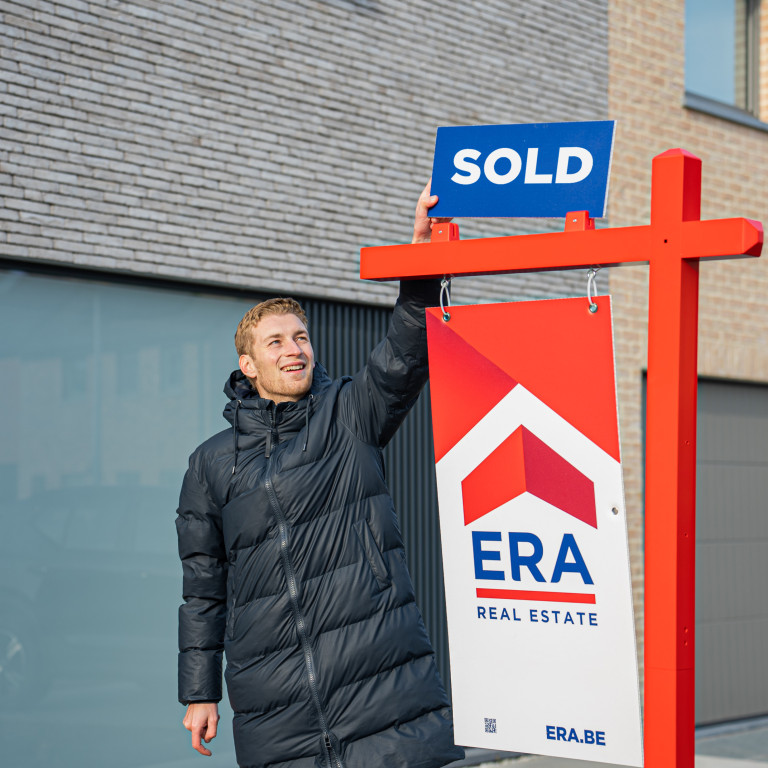 A man puts a sticker, with the word sold on an ERA billboard.
