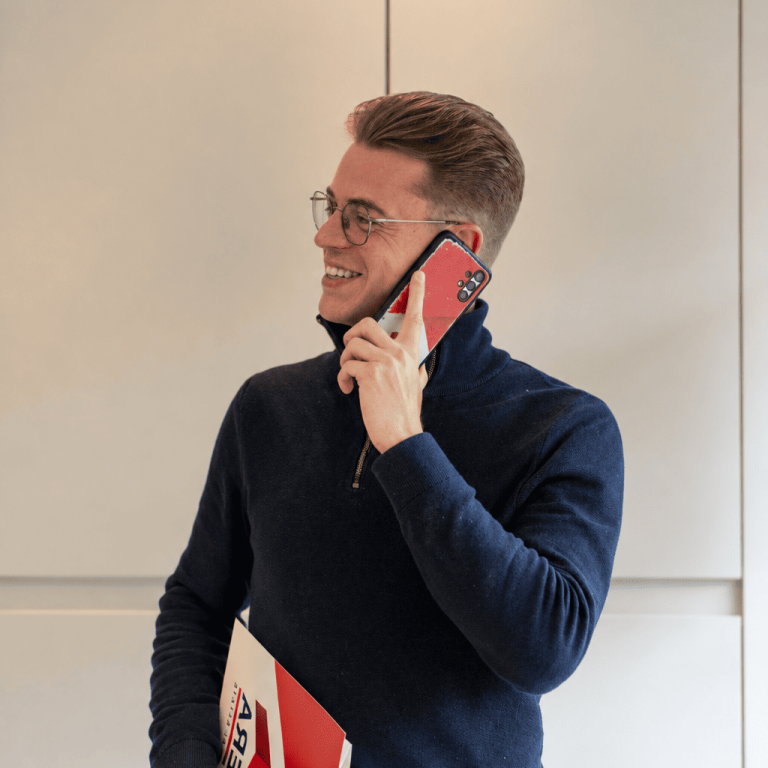 Agent immobilier souriant au téléphone, tenant un dossier ERA dans un bureau.