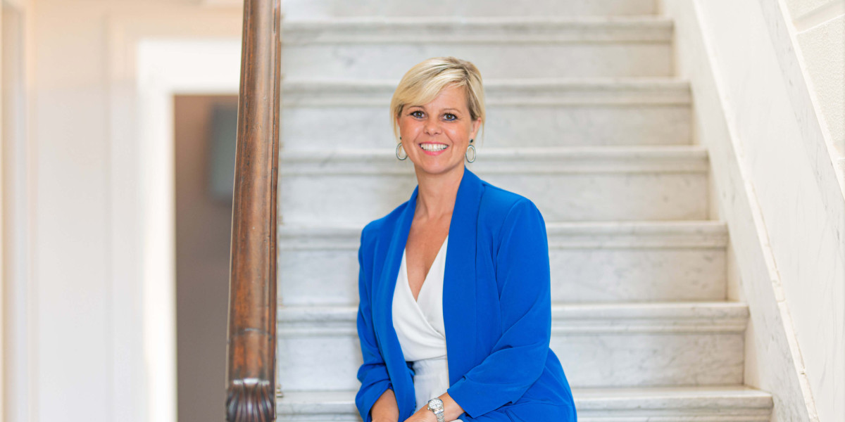 Topmakelaar Anneke zit op een trap in Huis Myle.