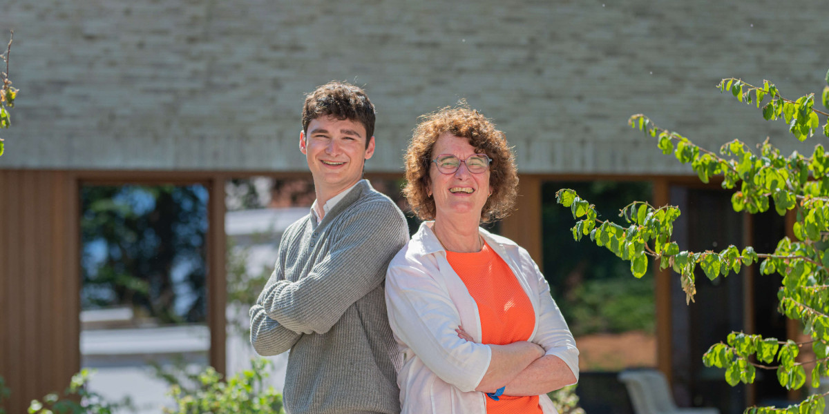Topmakelaars Dorine en Matthew lachen naar de camera terwijl ze rug tegen rug in de zon staan.