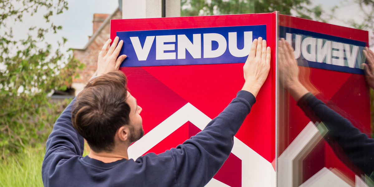 Un homme colle un autocollant avec le mot 'vendu' sur un panneau en V.
