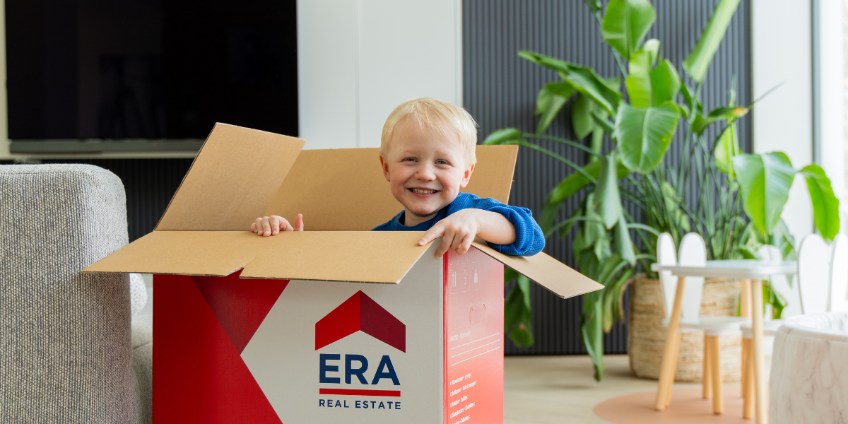 Un enfant jouant avec un carton de déménagement.