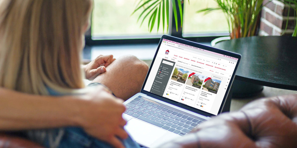 Een koppel zit samen in de zetel en bekijken de ERA immowebsite op een laptop.