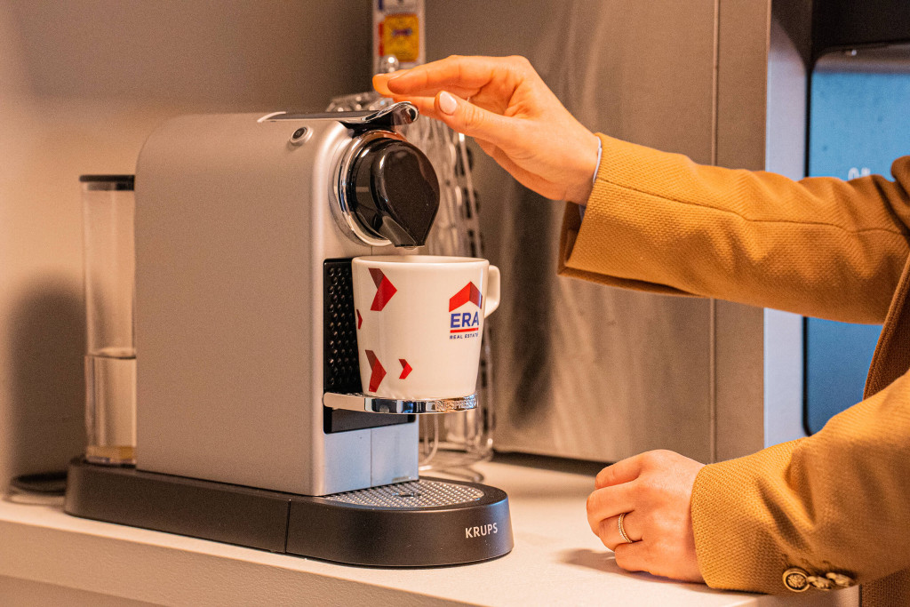 Een vrouw zet een koffie in een ERA koffietas.