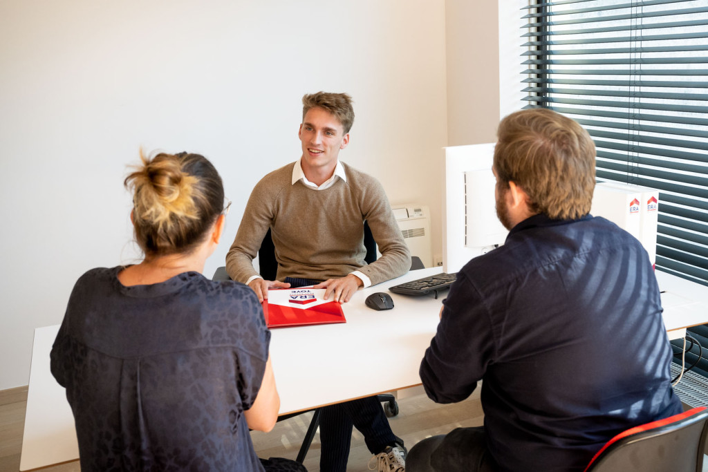 Een koppel zit aan tafel met een ERA makelaar om te onderhandelen over de verkoopprijs.