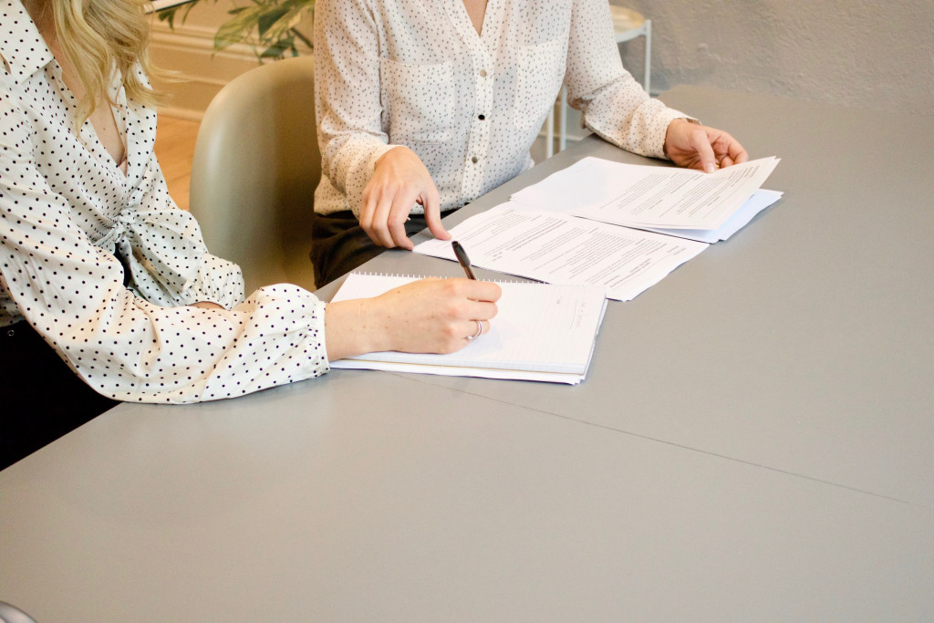 Twee vrouwen bekijken documenten voor de verkoop van een woning.