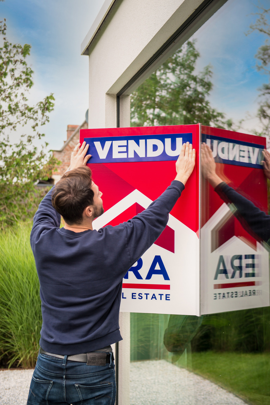 Un homme colle un autocollant avec le mot 'vendu' sur un panneau en V.