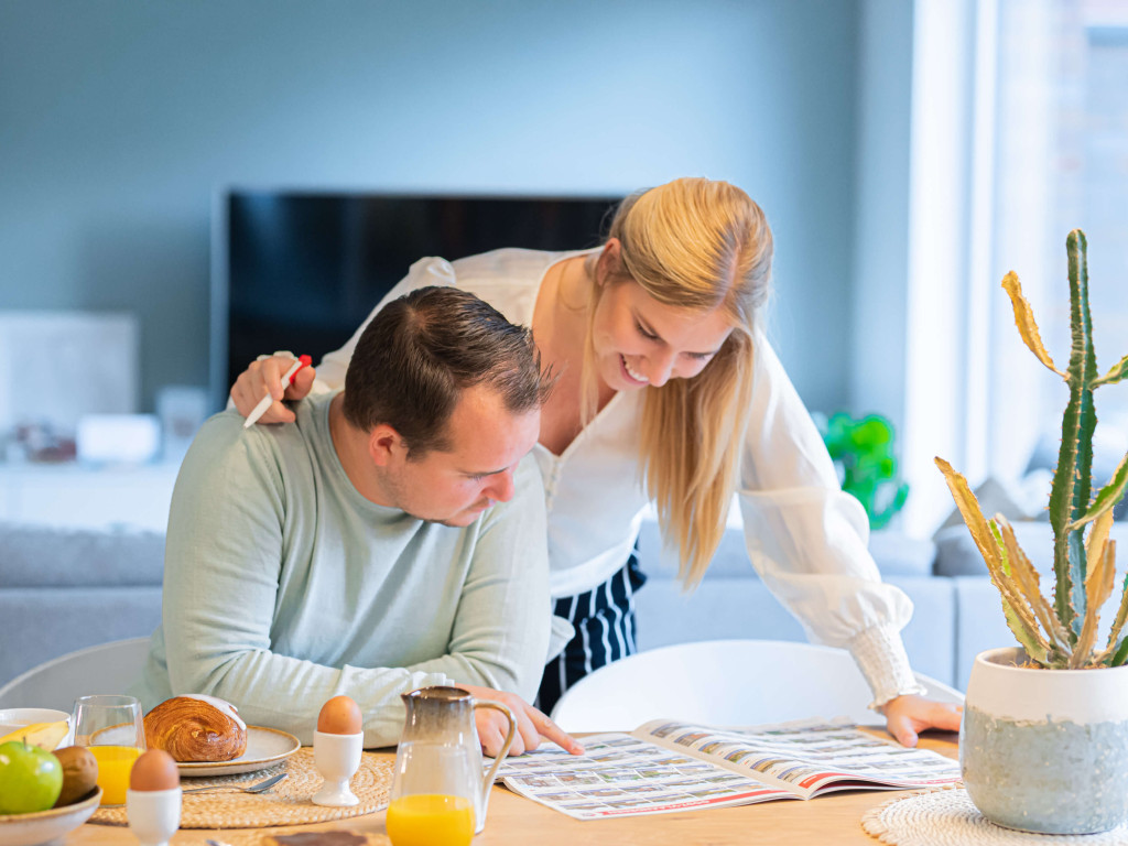 Een koppel leest samen de Open Huizen Dag krant.