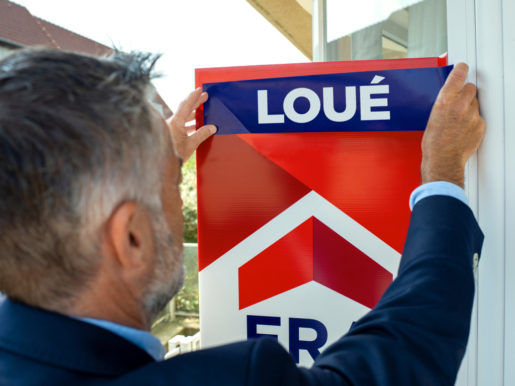 L'agent immobilier colle loué sur le panneau