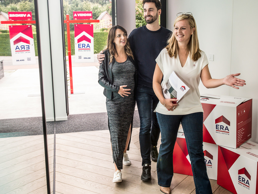 Un agent immobilier ERA fait visiter à un couple un bien à vendre.