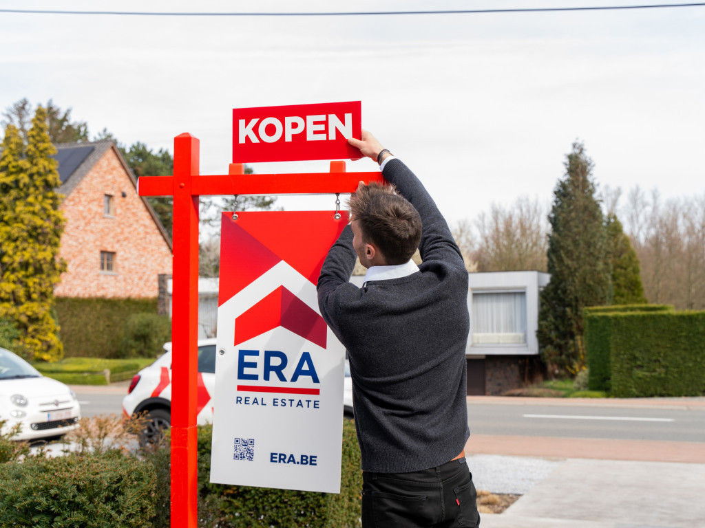 Man hangt koop bord op.