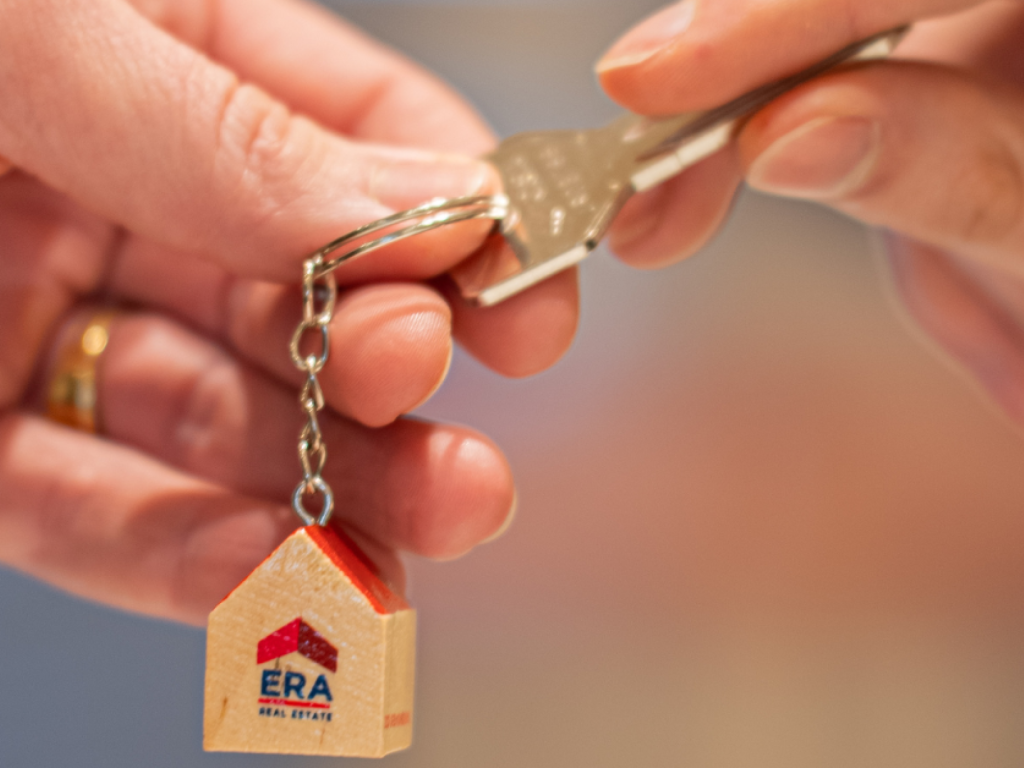 Une personne en possession d'une clé de maison ERA la remet à quelqu'un.