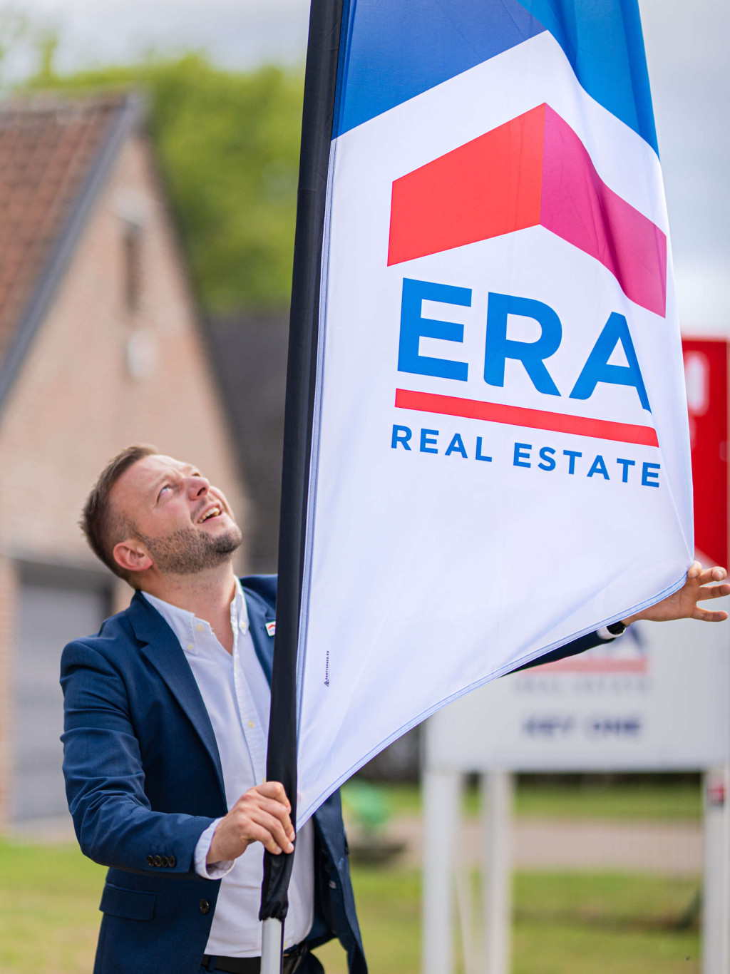 Een ERA makelaar zet een ERA Open Huizen Dag beachvlag op zijn plaats.