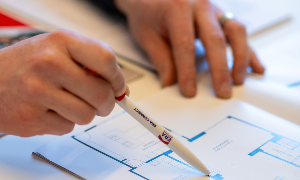 Dries duidt een ruimte aan op het bouwplan.