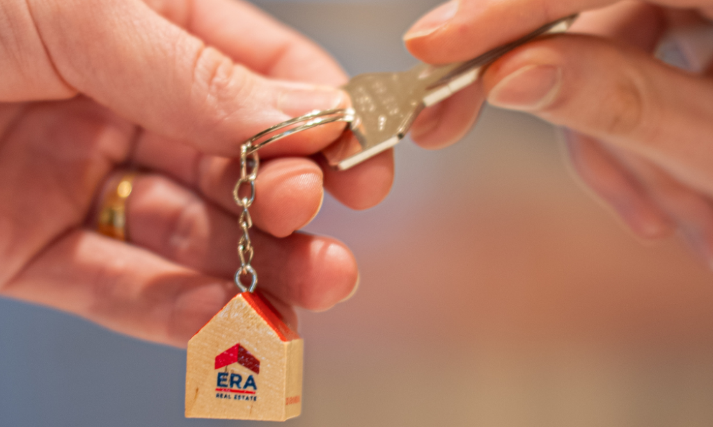 Une personne en possession d'une clé de maison ERA la remet à quelqu'un.