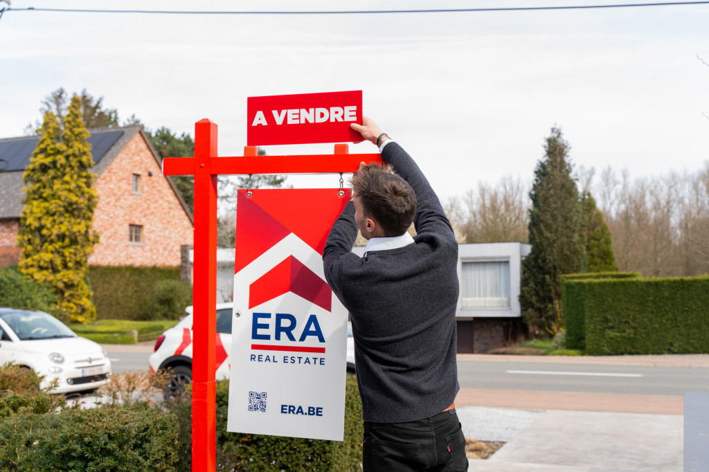 L'agent immobilier place à vendre sur le poteau de jardin