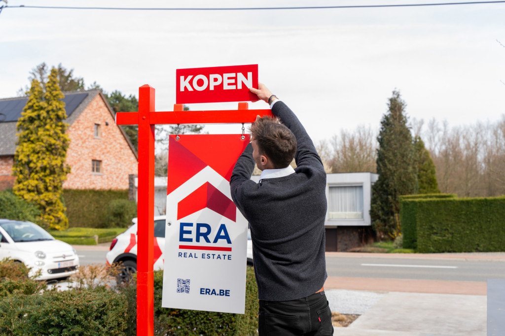 Makelaar plaatst kopen op tuinpaal