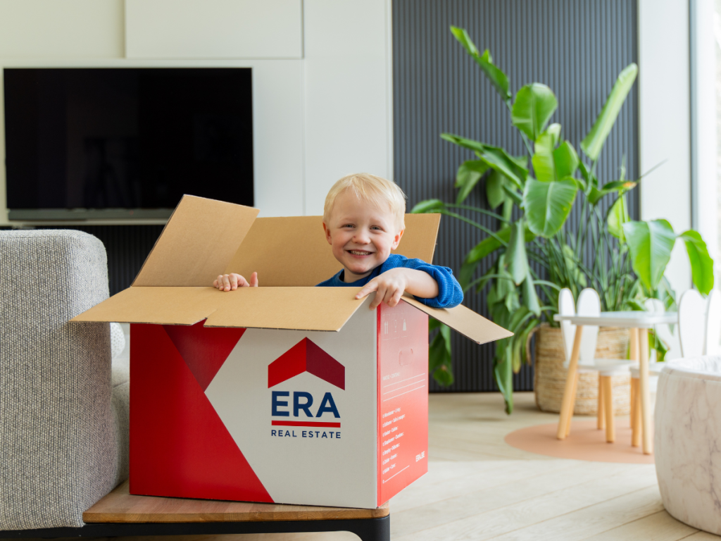 Un enfant jouant avec un carton de déménagement.