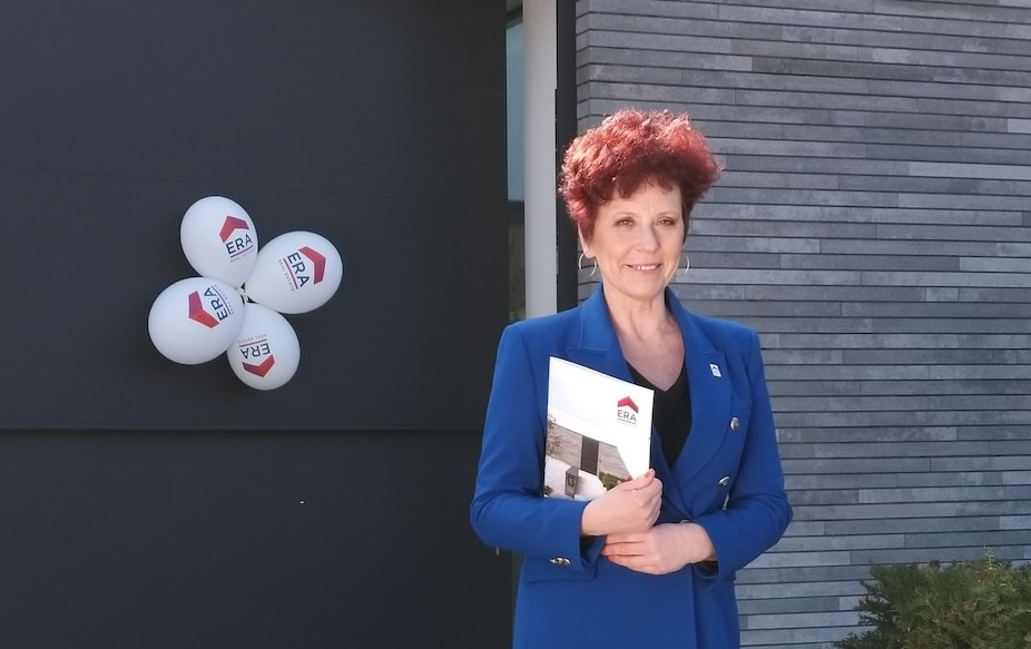 Makelaar met brochure in de hand voor een poort.